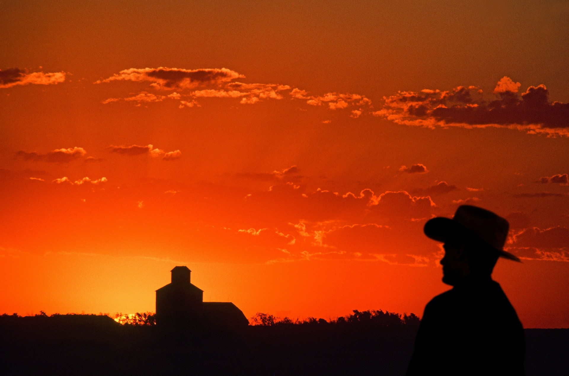 Silhouetted farmer, grain elevator