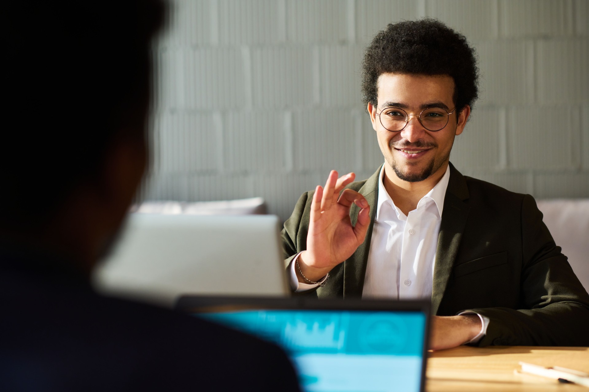 Young smilling businessman showing okay sign to his colleague or applicant